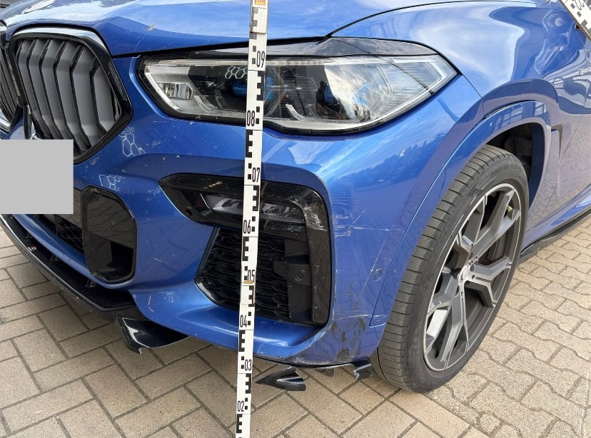 Frontschaden an einem blauen BMW mit Messlatte