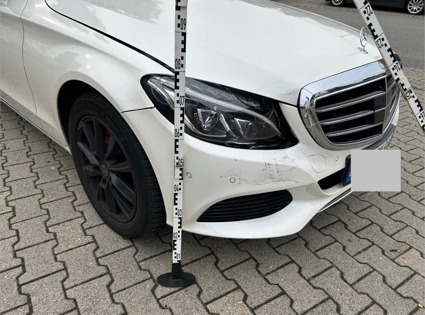 Frontschaden an einer weißen Mercedes C-Klasse mit Messlatte